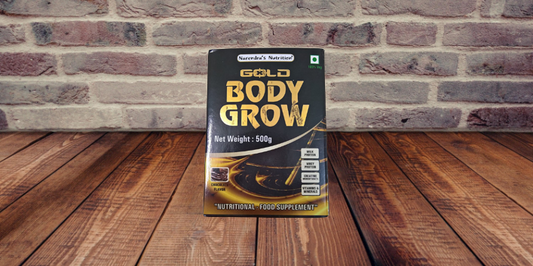 mage of a container of Body Grow Gold Body Gain Powder, a protein supplement for muscle building and development, with a scoop of powder resting on top of it.